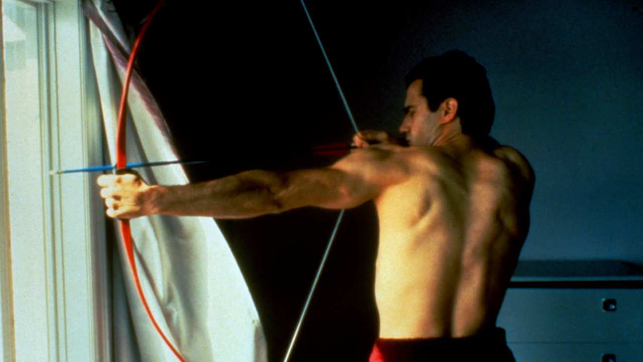 a man aiming a bow and arrow out a window